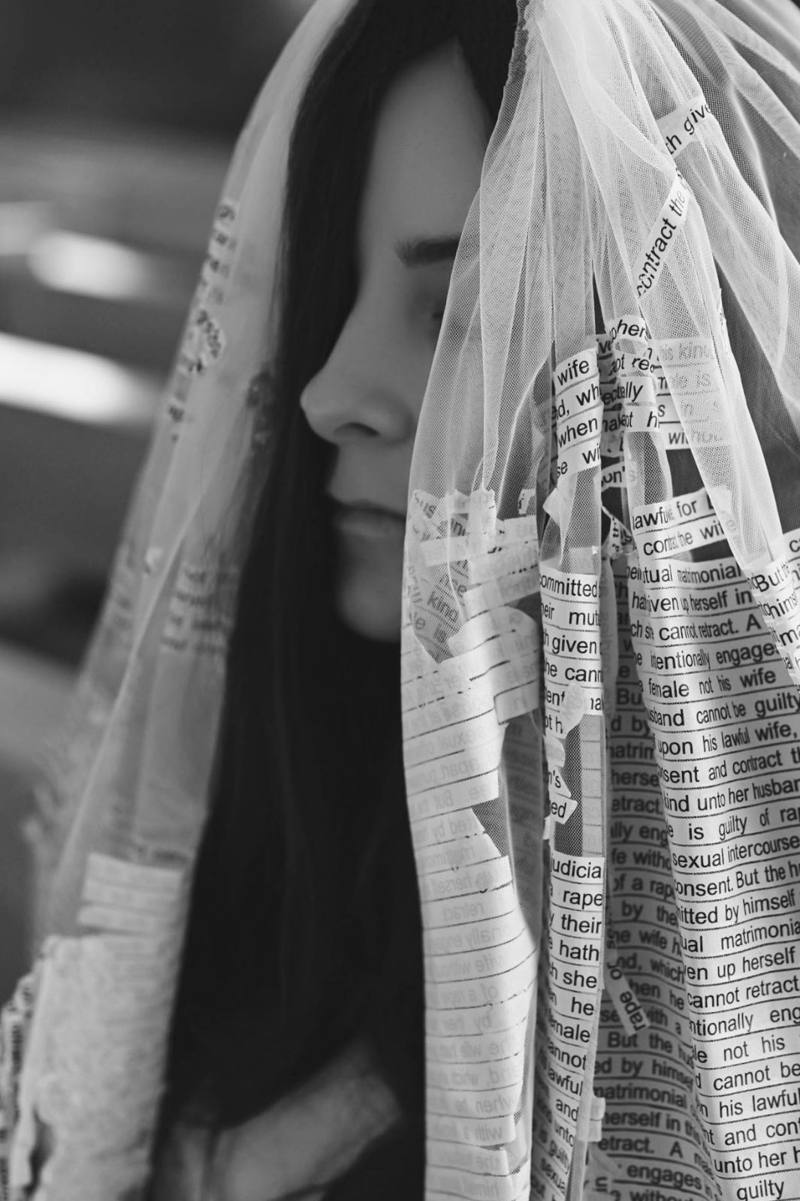 Profile of the veiled bride, the printed law fraying across the tulle