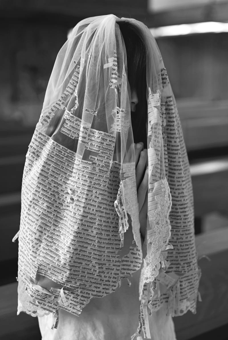 A bride, fully veiled in the legal text with her face obscured
