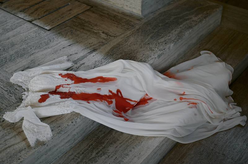 Blood-stained wedding dress draped over marble steps